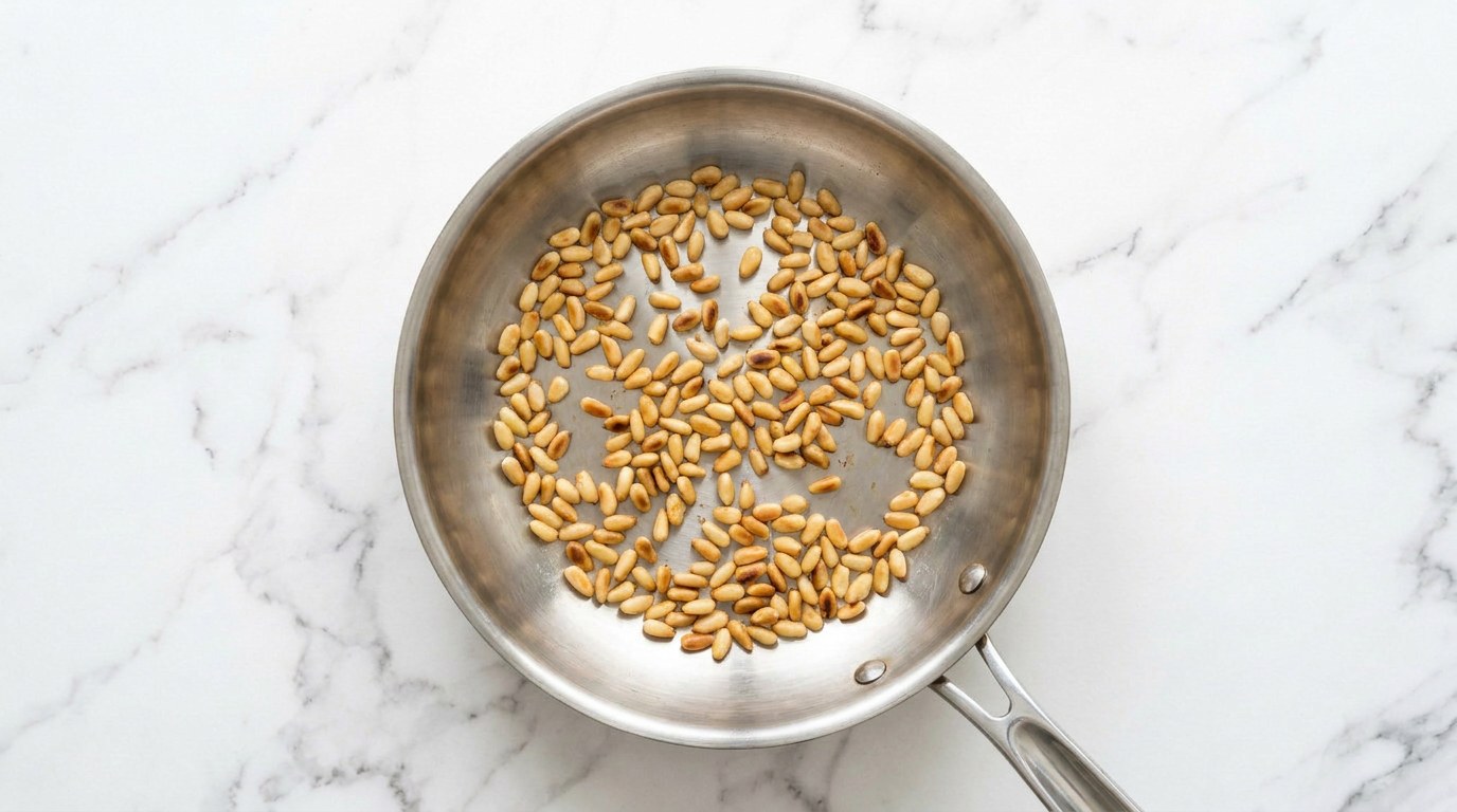 Step 2: Toast the pine nuts golden in a dry frying pan.